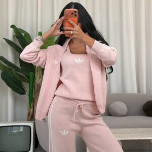 Pale pink zip jacket worn open over a sleeveless knit top and drawstring pants with white side stripes.