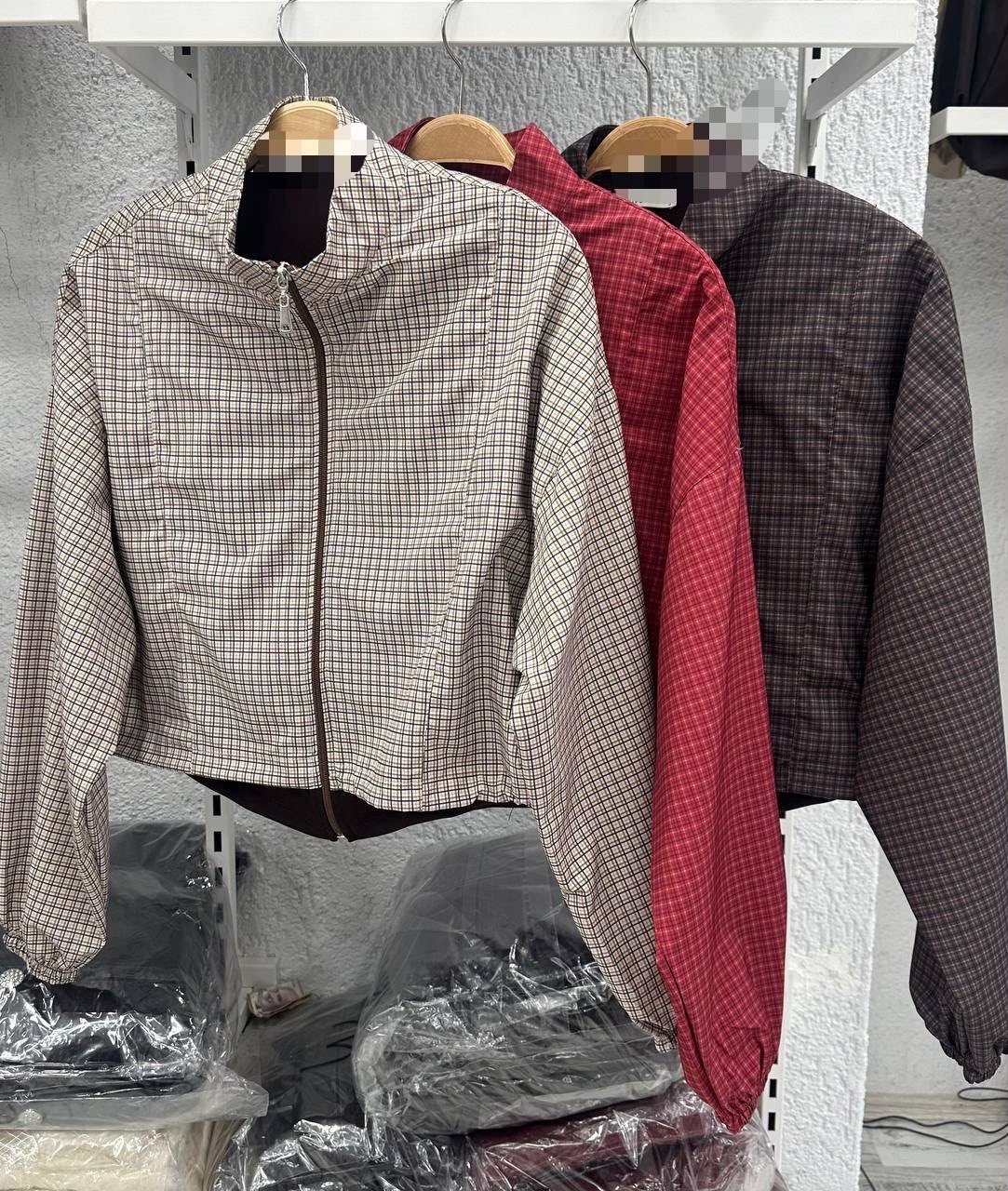 creme-rot-anthrazit-karierte-jacke-modell-2746-grosshandel-tuerkei Drei karierte Cropped-Jacken an Kleiderbügeln in Creme, Rot und Anthrazit mit Frontreißverschlüssen. Großhandel Türkei verfügbar.