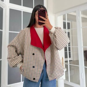 Closer front view showing the jacket's beige check pattern, wide red lapels, and black button closure.