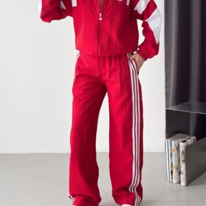 Red zip-front jacket and wide-leg trousers feature white shoulder panels, sleeve accents, and side stripes.