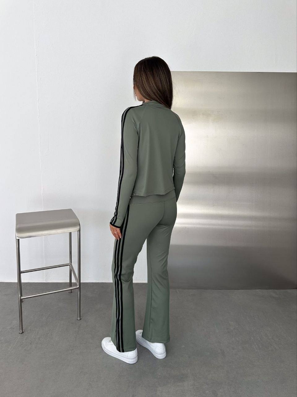 sage-tracksuit-back-7583 Rear view of a sage jacket and flared trousers with black stripes running along the sleeves and legs.