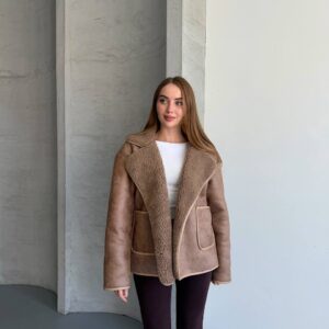 Front view of a taupe suede-look jacket with broad textured lapels, pale piping, and two patch pockets.