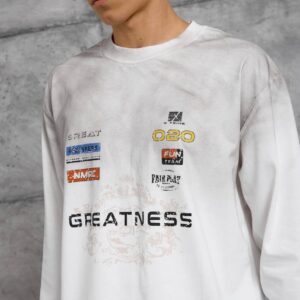 Close view of a white shirt showing small multicolor chest motifs and a large dark graphic over a faint ornamental print.